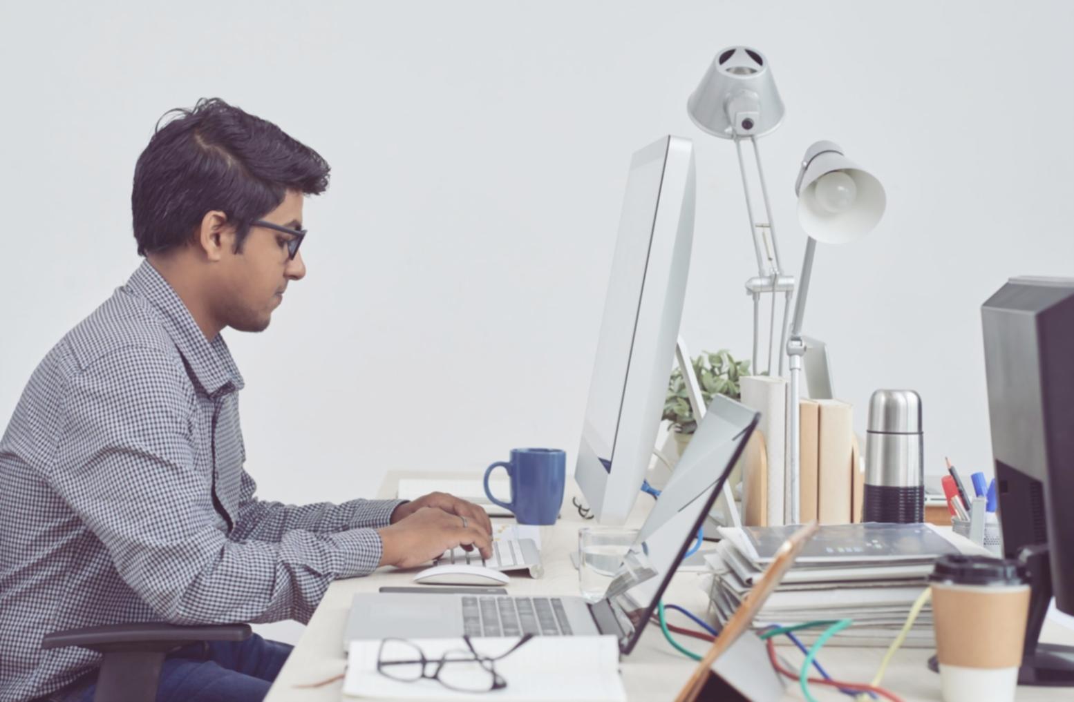 Security engineer analyzing blockchain code on multiple monitors showing vulnerability patterns and test results